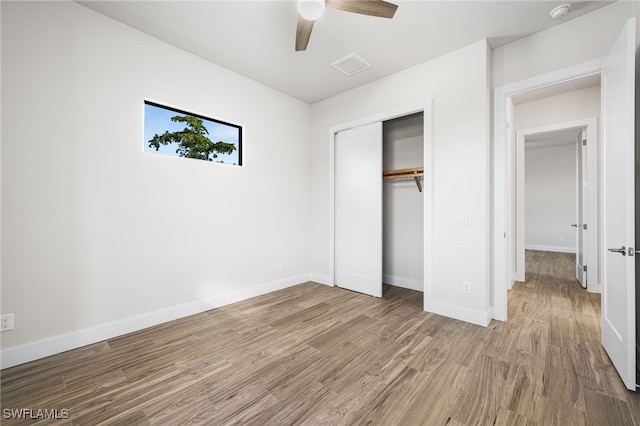 unfurnished bedroom with ceiling fan, a closet, and light wood-type flooring