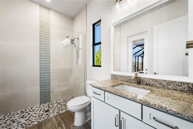 bathroom featuring toilet, vanity, tiled shower, and hardwood / wood-style floors