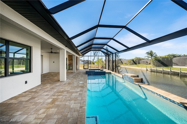 view of pool featuring ceiling fan, an in ground hot tub, glass enclosure, a water view, and a patio