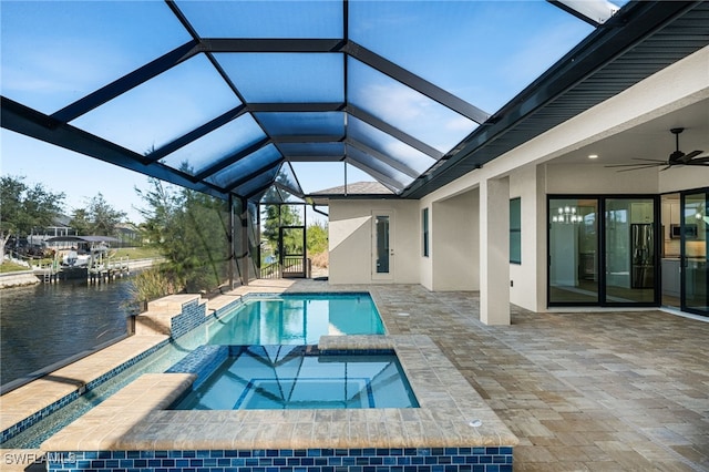 view of swimming pool with a patio area, an in ground hot tub, a water view, ceiling fan, and a lanai