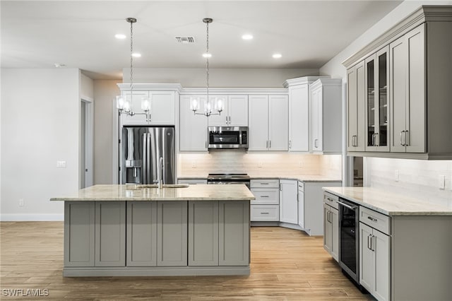 kitchen featuring appliances with stainless steel finishes, gray cabinetry, beverage cooler, and a kitchen island with sink