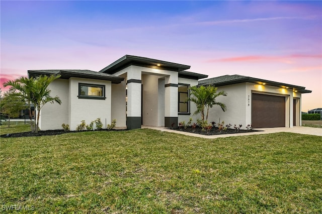 prairie-style home with a garage and a lawn