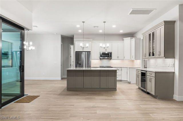 kitchen with hanging light fixtures, appliances with stainless steel finishes, gray cabinetry, and a kitchen island