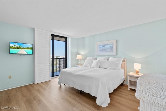 bedroom featuring light wood-style floors, access to outside, expansive windows, and baseboards