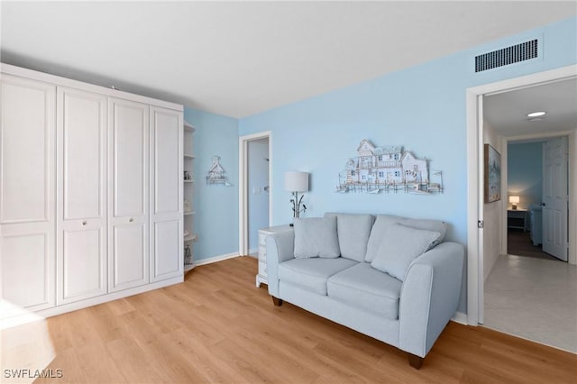 living area featuring light wood-type flooring, visible vents, and baseboards