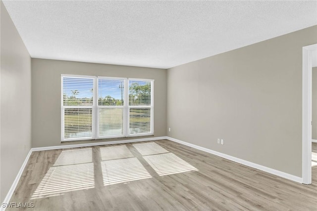 unfurnished room with a textured ceiling and light hardwood / wood-style flooring