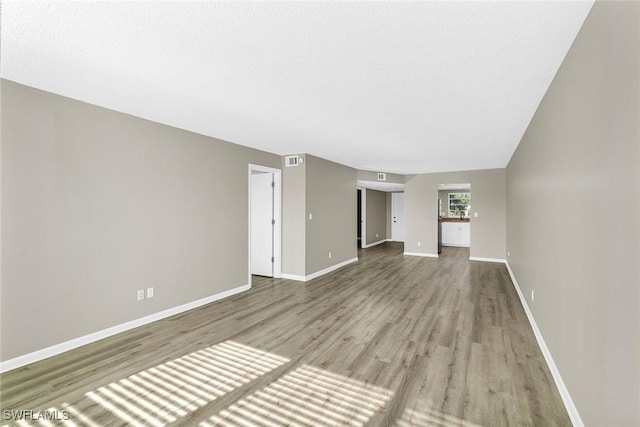 unfurnished living room with light hardwood / wood-style floors and a textured ceiling