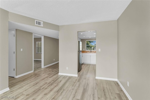 unfurnished living room with light hardwood / wood-style floors and a textured ceiling