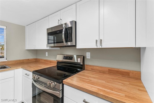 kitchen featuring white cabinetry, appliances with stainless steel finishes, and butcher block countertops