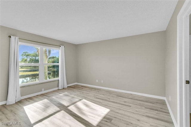 empty room featuring a water view and light hardwood / wood-style floors