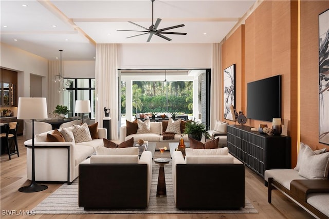 living room with light wood-type flooring and ceiling fan with notable chandelier