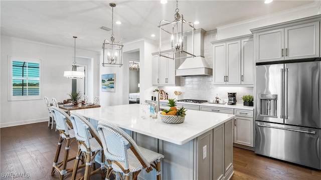 kitchen with a kitchen breakfast bar, custom range hood, stainless steel appliances, decorative light fixtures, and gray cabinets