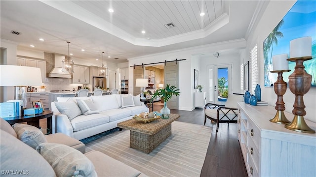 living room featuring wooden ceiling, a raised ceiling, a barn door, crown molding, and hardwood / wood-style flooring