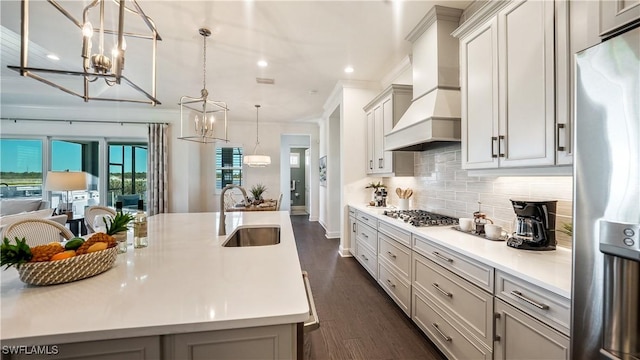 kitchen featuring sink, hanging light fixtures, stainless steel appliances, a spacious island, and custom exhaust hood