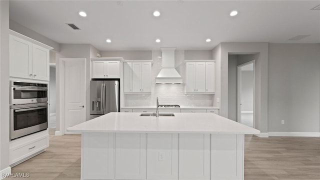 4075 Pegasus Way, Naples, FL 34120 - kitchen featuring stainless steel appliances, a sink, premium range hood, white cabinetry, and a kitchen island with sink
