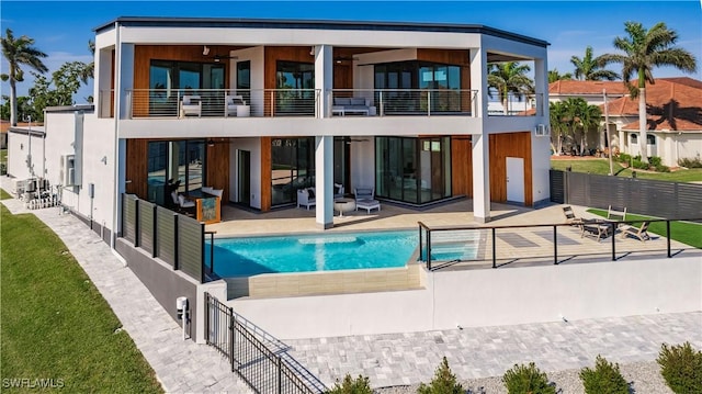 back of property featuring a fenced in pool, a patio, and a balcony