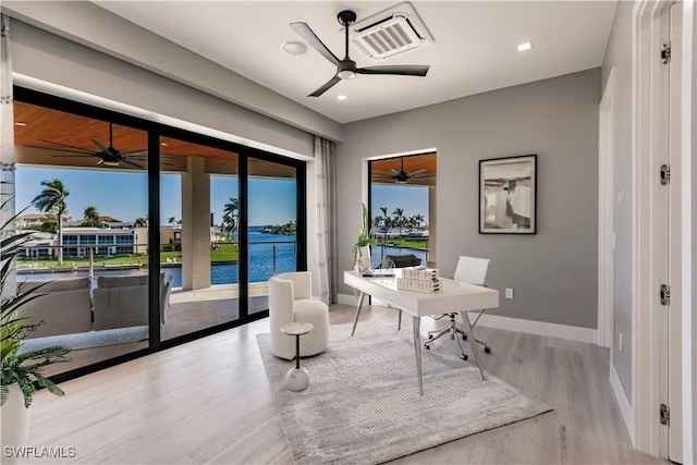 home office with light hardwood / wood-style floors and a water view