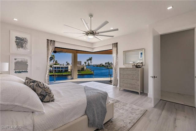 bedroom with a water view, ceiling fan, access to exterior, and light wood-type flooring