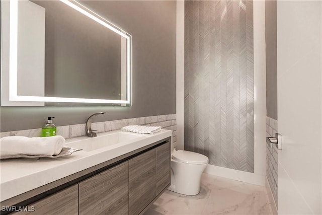 bathroom featuring vanity, tile walls, and toilet