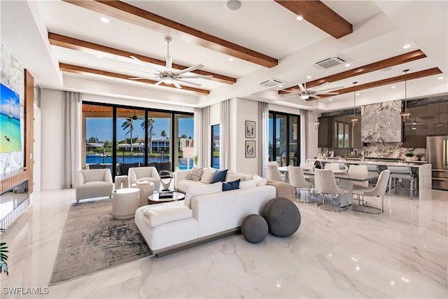 living room with beam ceiling, a wealth of natural light, ceiling fan, and a water view