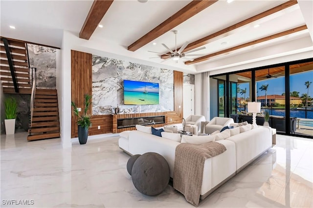 living room featuring a brick fireplace, beamed ceiling, and ceiling fan