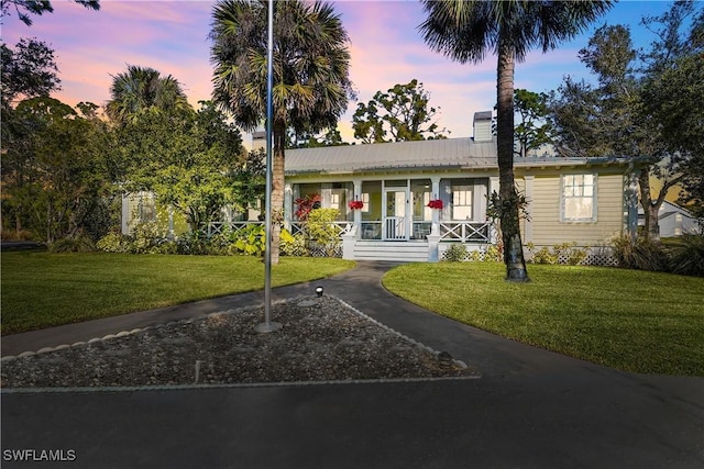 view of front of property featuring covered porch and a yard