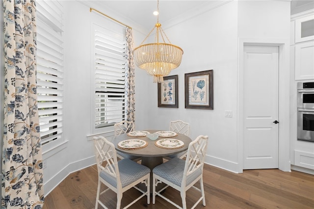 dining space with a notable chandelier, crown molding, and hardwood / wood-style floors