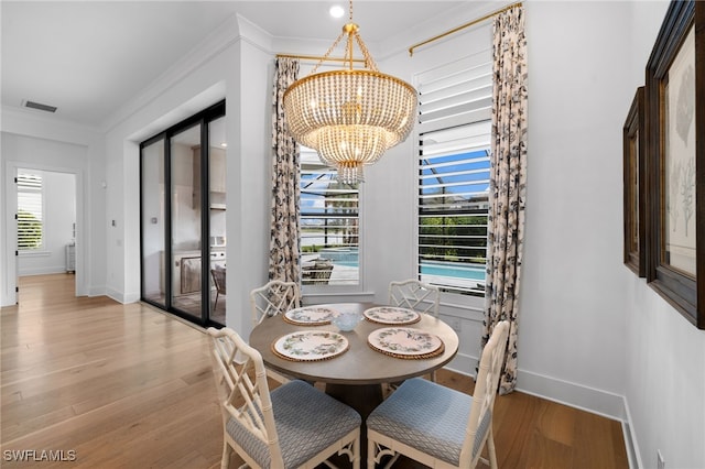 dining area featuring light hardwood / wood-style flooring, plenty of natural light, crown molding, and a chandelier