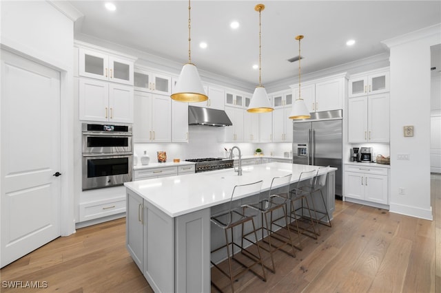 kitchen with a center island with sink, white cabinets, and pendant lighting