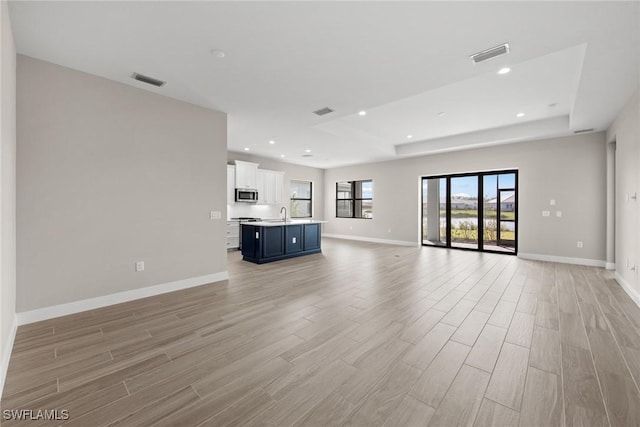 unfurnished living room featuring sink and light hardwood / wood-style floors