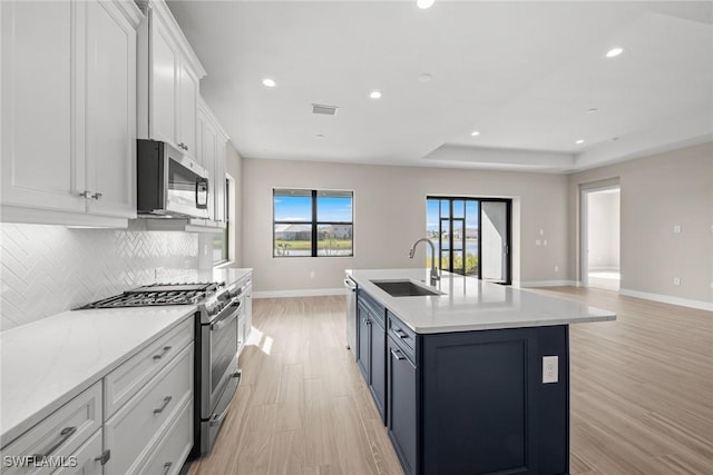 kitchen featuring tasteful backsplash, white cabinetry, sink, stainless steel appliances, and light hardwood / wood-style flooring