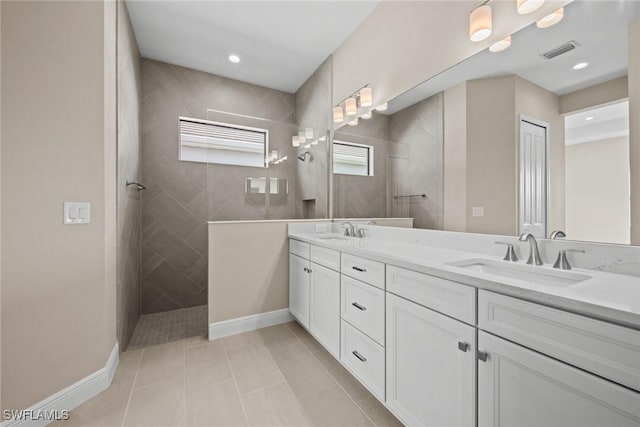 bathroom with vanity, a tile shower, and tile patterned floors