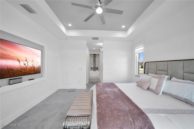 bedroom with a raised ceiling, connected bathroom, and ceiling fan