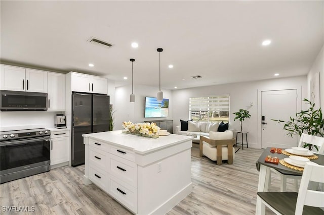 kitchen featuring black refrigerator, white cabinets, hanging light fixtures, stainless steel electric range, and light hardwood / wood-style flooring