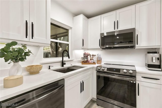 kitchen with appliances with stainless steel finishes, sink, and white cabinetry