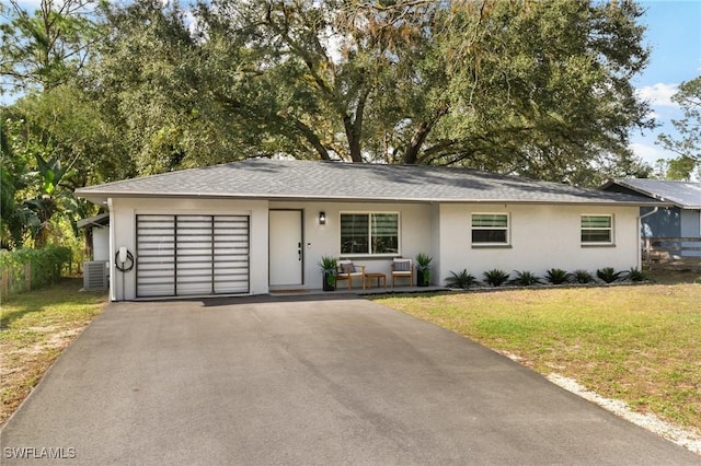 ranch-style home featuring a garage, a front yard, and central AC