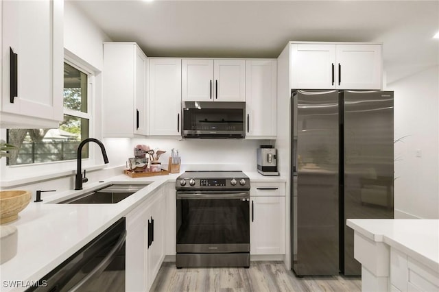 kitchen featuring white cabinets, appliances with stainless steel finishes, sink, and light hardwood / wood-style flooring