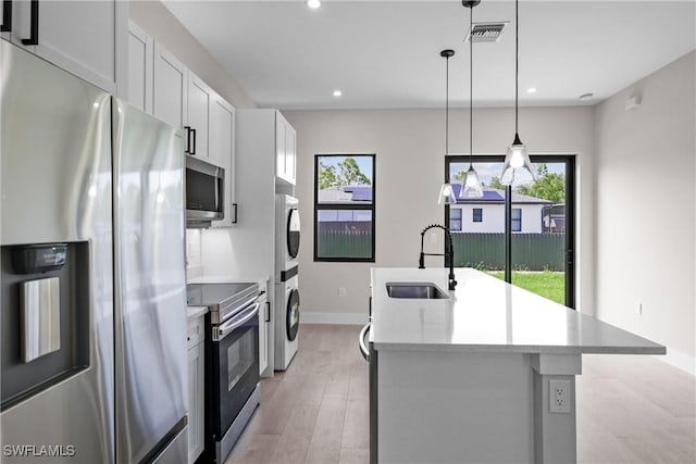 1201 E 7th St, Lehigh Acres, FL 33972 - kitchen with stainless steel appliances, a sink, stacked washer and clothes dryer, an island with sink, and plenty of natural light