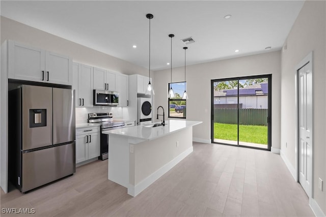 1201 E 7th St, Lehigh Acres, FL 33972 - kitchen featuring appliances with stainless steel finishes, a sink, a center island with sink, light wood-type flooring, and light countertops