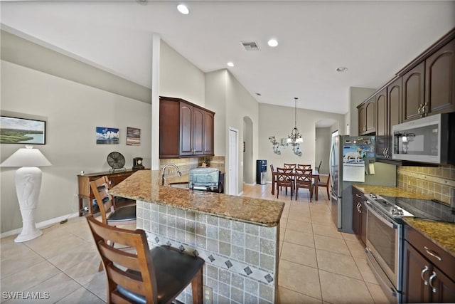 kitchen with decorative backsplash, appliances with stainless steel finishes, decorative light fixtures, light tile patterned flooring, and kitchen peninsula