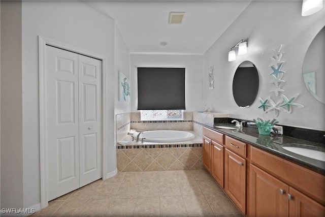 bathroom featuring tile patterned floors, vanity, and tiled tub