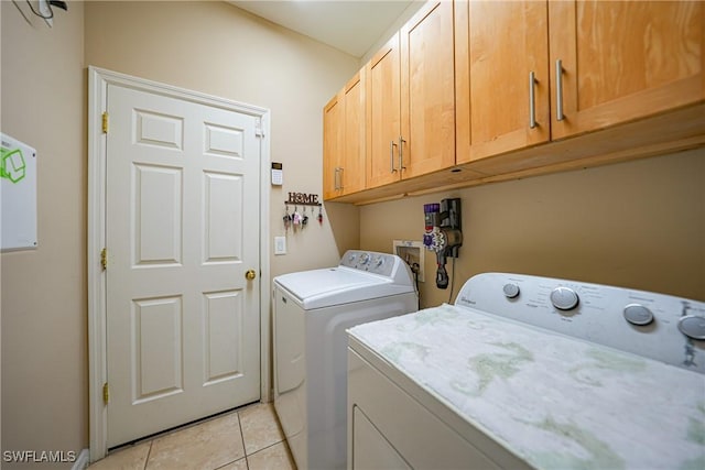 washroom with cabinets, light tile patterned floors, and separate washer and dryer