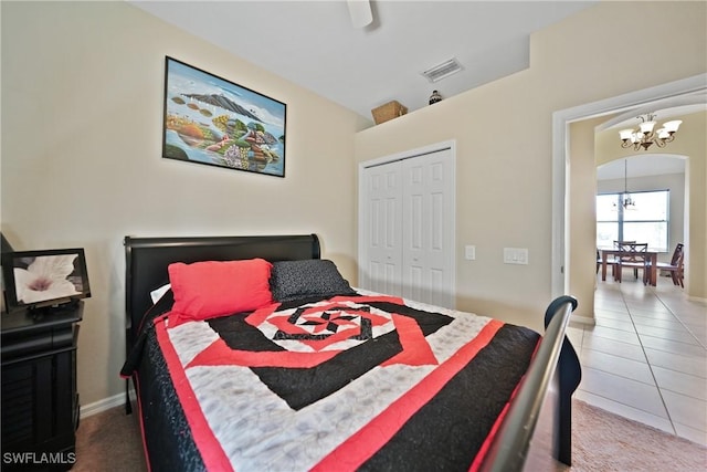 tiled bedroom featuring ceiling fan with notable chandelier and a closet