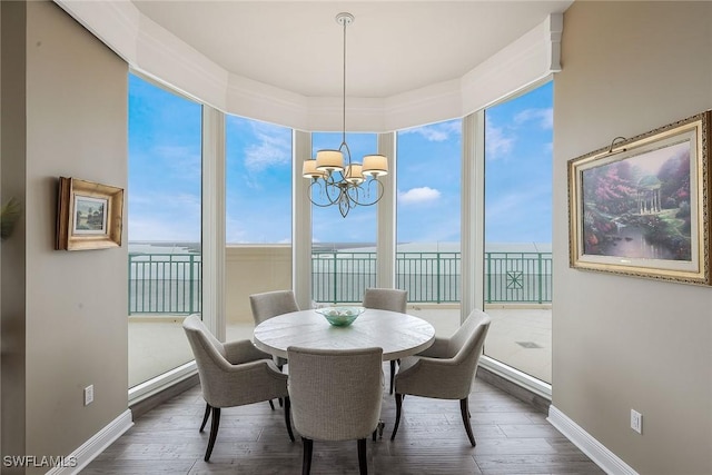 dining space featuring dark hardwood / wood-style flooring, a water view, and an inviting chandelier