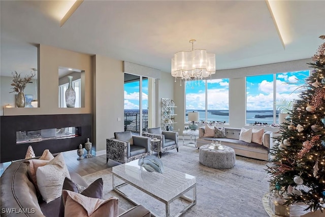 living room featuring a chandelier, a water view, and light hardwood / wood-style floors