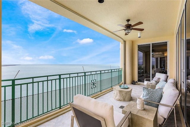 balcony with ceiling fan, a water view, and an outdoor living space