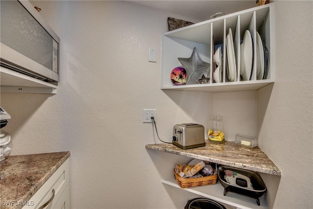 interior space featuring white cabinets and stone countertops