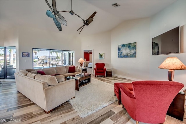 living room with ceiling fan, high vaulted ceiling, and light hardwood / wood-style flooring