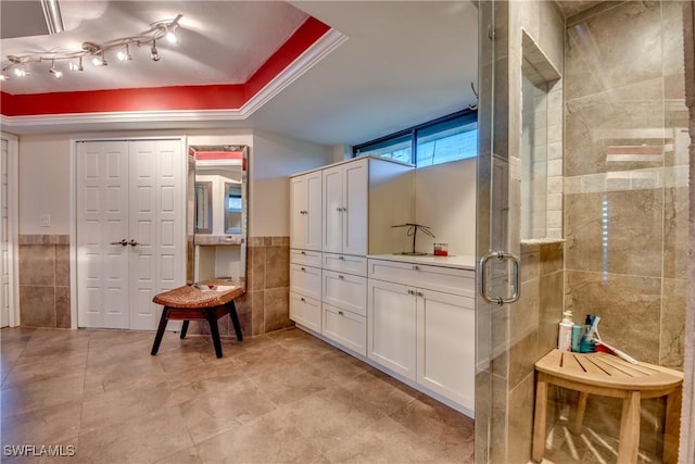 interior space featuring a tray ceiling, tile walls, and a shower with door