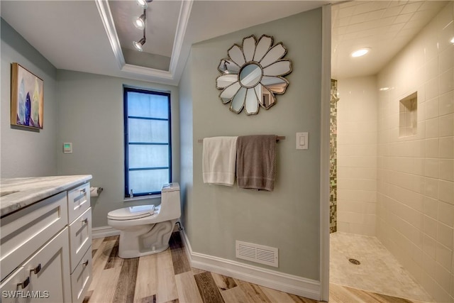 bathroom with walk in shower, hardwood / wood-style floors, toilet, a tray ceiling, and vanity